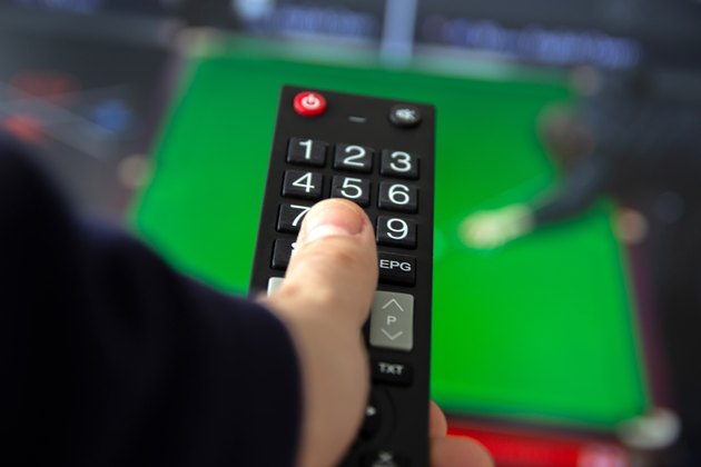 Man watching TV set and using remote control.
