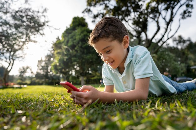 Happy boy at the park watching videos online