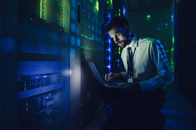 Handsome man is working in data centre with laptop.