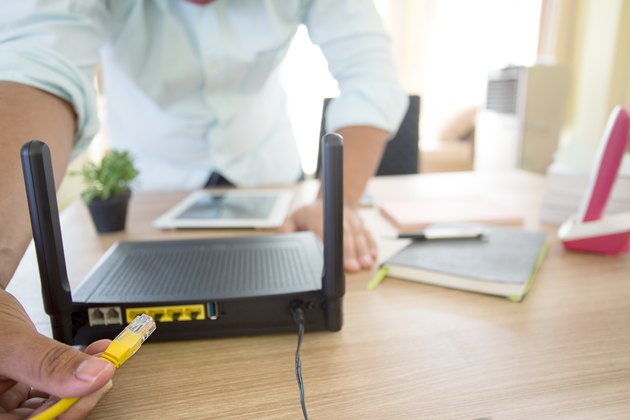 hand and lan network cable with people work on wireless router,