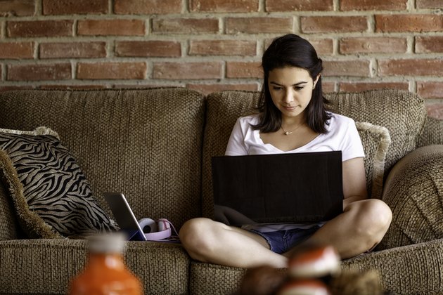 Hispanic young woman working on a laptop computer at home. Home office concepts