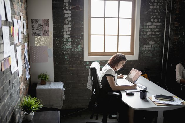 Dedicated creative businesswoman working at laptop in office