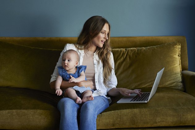 Mother sitting with new born baby and laptop