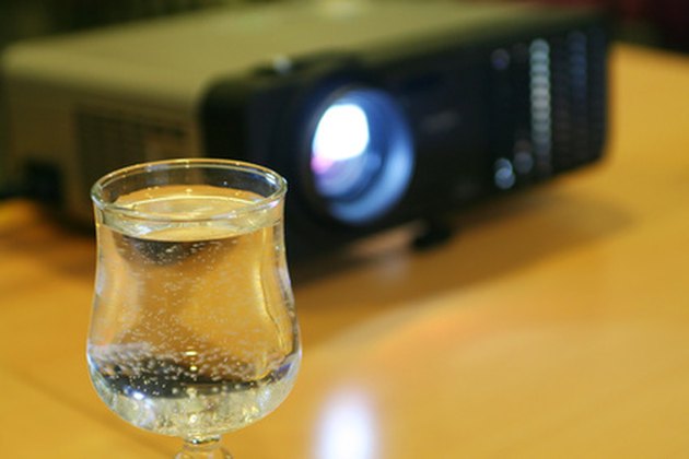 glass of water on table with projector behind