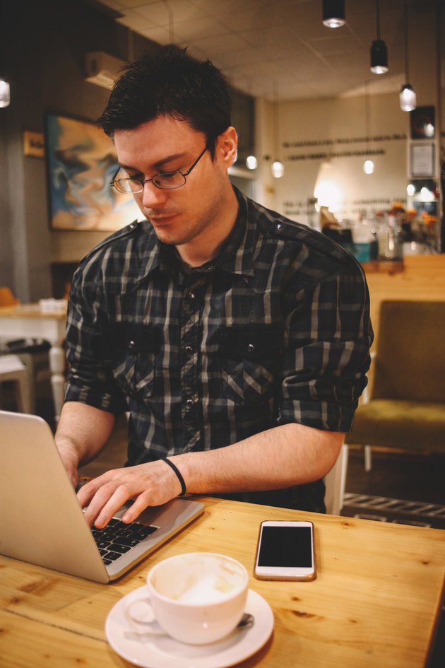 Young man sitting in a coffee shop using laptop