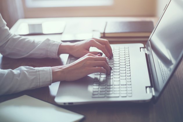 Woman working in home office hand on keyboard close up