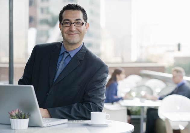 Smiling business man with computer in cafe.
