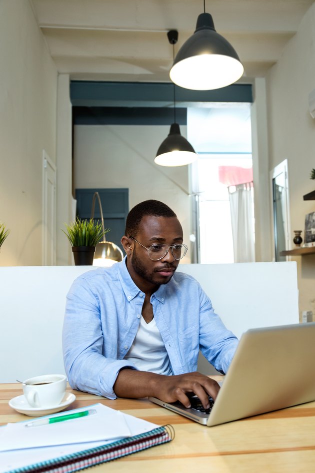 Handsome young black man working with laptop at home.