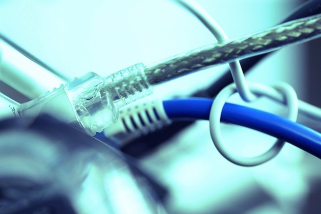 Blue tone close-up of ethernet and firewire cables plugged into ports on the back of a computer.