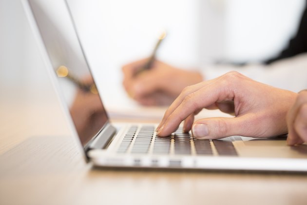 Woman using laptop in office during a meeting. Close-up hands