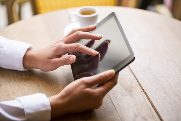 Hands woman using her tablet pc in bar, coffee