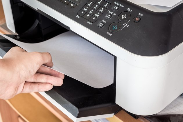 Hand holding paper sheets into printer tray
