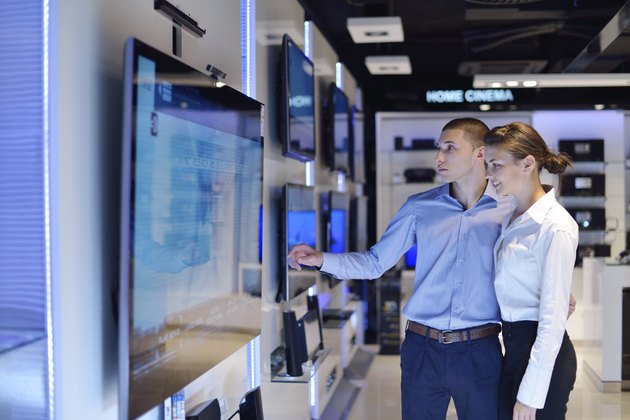 Young couple in consumer electronics store buy tv
