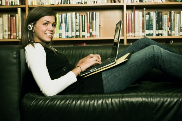 Student sitting on a couch with a laptop and listening to music