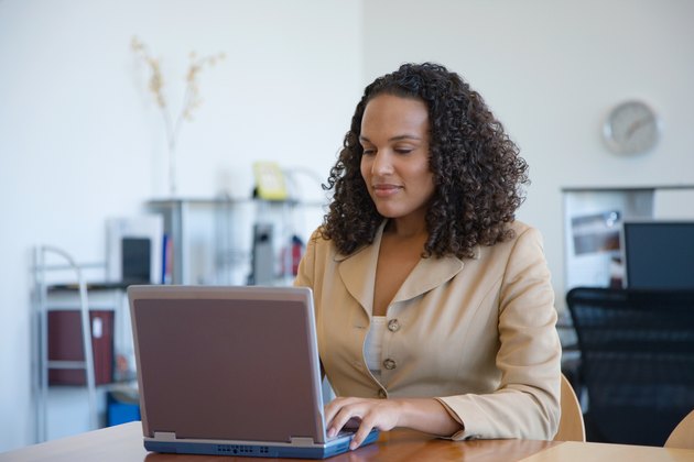 Businesswoman working at laptop on table in office