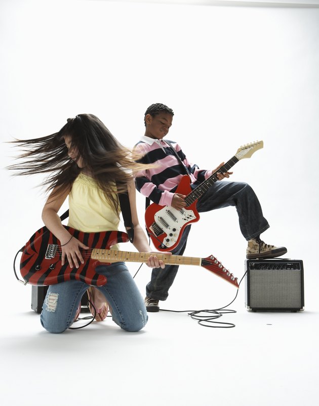 Boy and girl (9-11) playing electric guitars