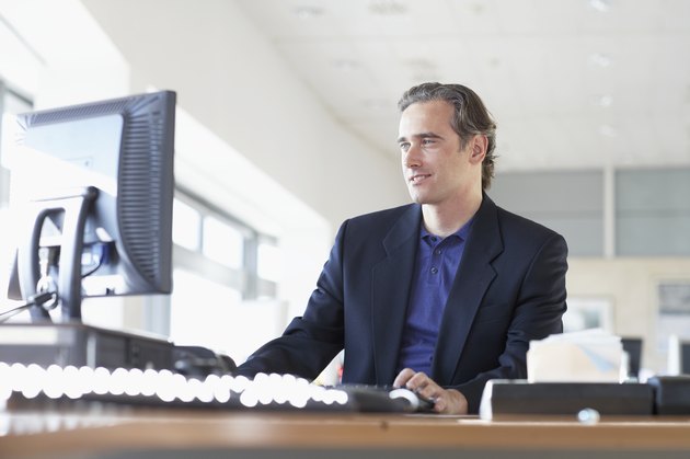 Businessman at desk in office, looking at monitor, low angle view