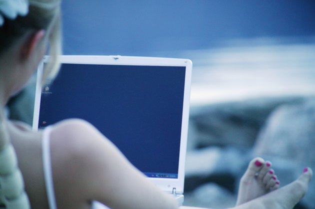 Woman works on lap top computer at the beach