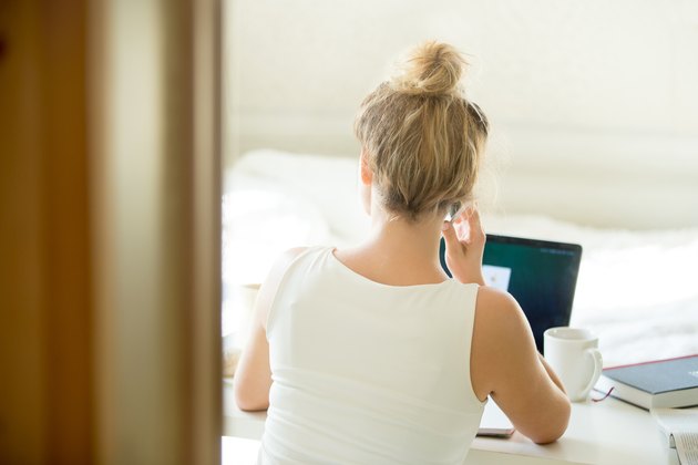 Woman sitting back talking on the phone at table.