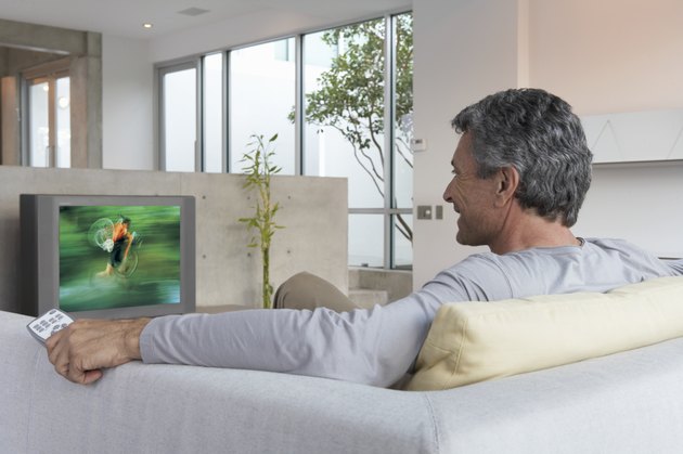Man relaxing on sofa watching television, rear view
