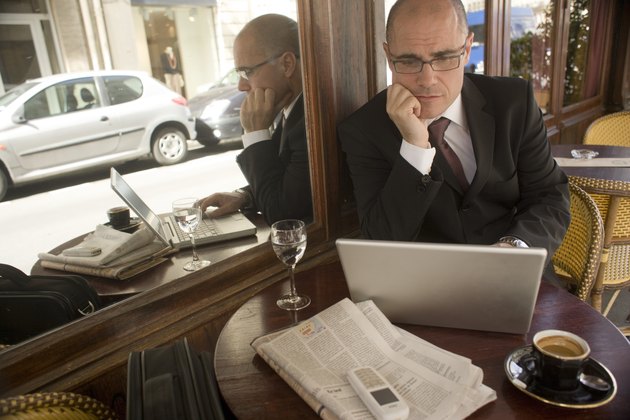 Mature businessman sitting at cafe table looking at laptop