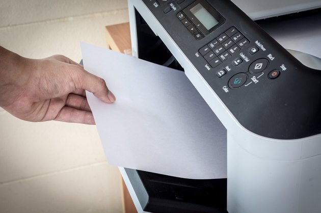 Hand holding paper sheets into printer tray