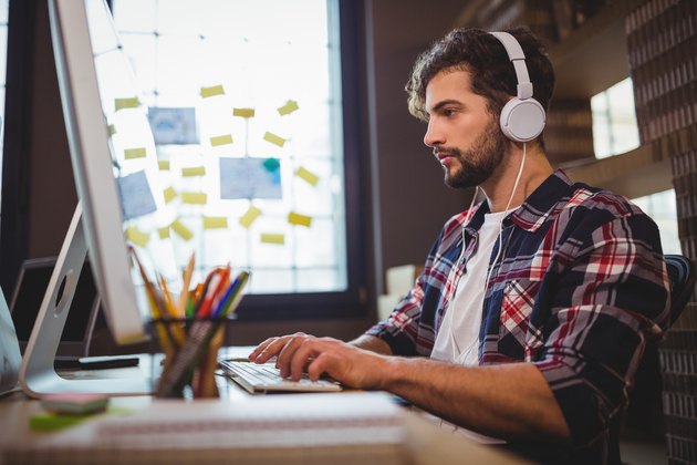 Creative businessman using computer while listening music