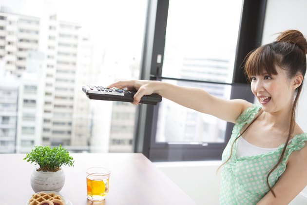 Young woman holding remote control, smiling