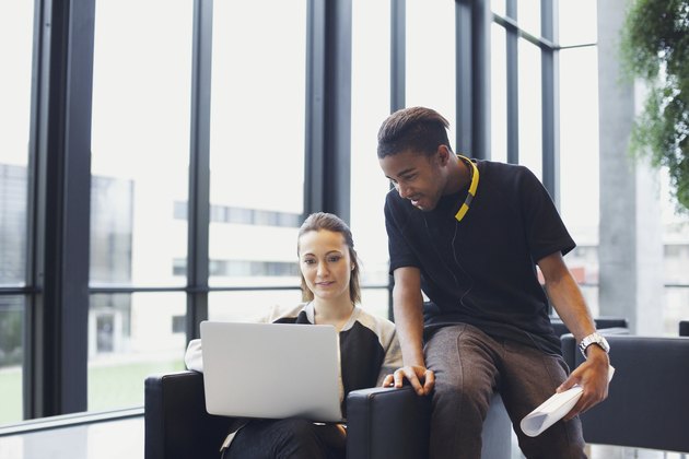 Two young students using laptop in campus