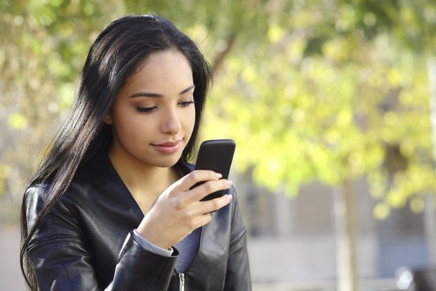 Beautiful woman texting on a smart phone in a park