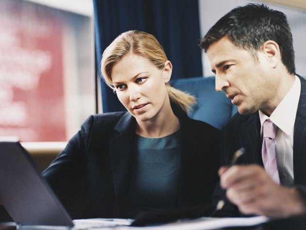 Two Business Executives Sitting on a Passenger Train and Working on a Laptop