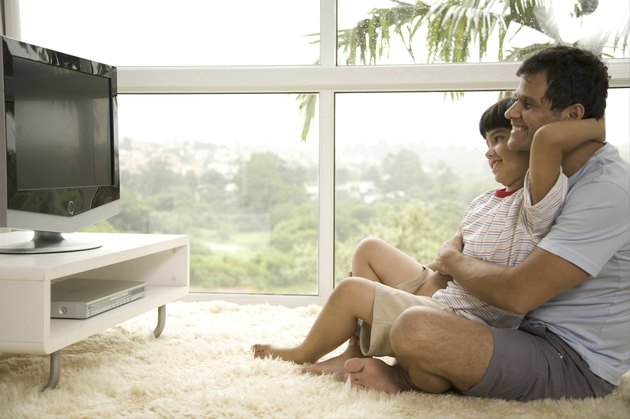 Side profile of mature man with his son (8-9) watching television