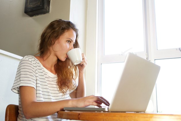 Young woman working on laptop and drinking coffee