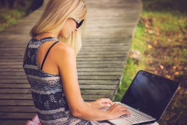 Young, beautiful woman resting in the park and using laptop.