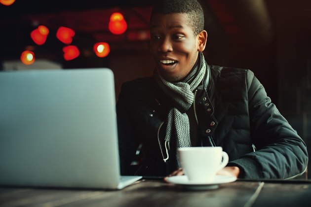 Indoor portrait of young black man sitting in cafe, drinking