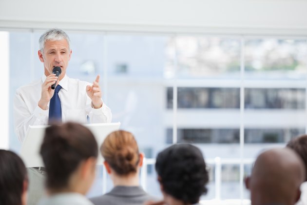 Mature businessman using a microphone to talk to his colleagues
