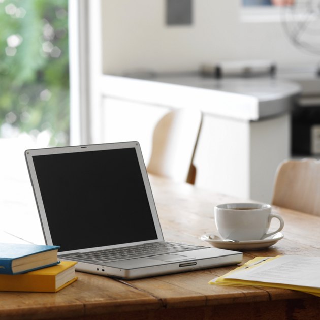 close up of a laptop on a kitchen table with a cup of coffee