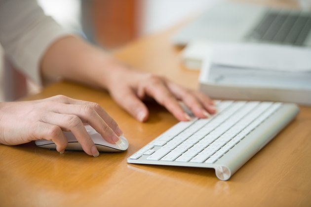 Close up of woman hands using mouse and keyboard.