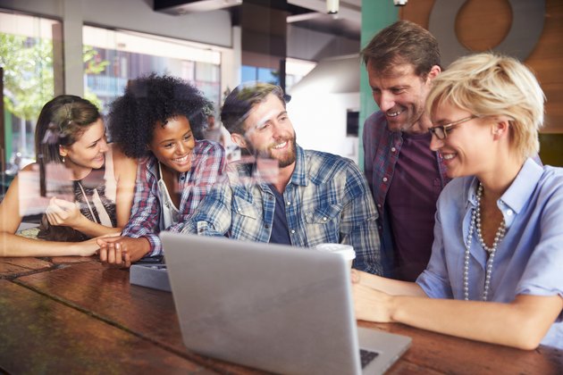 Group Of Businesspeople Working On Laptop In Coffee Shop