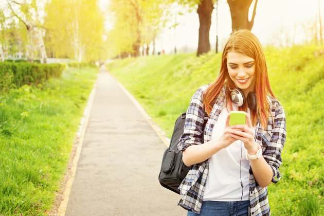 Happy redhead high school girl with smart phone texting