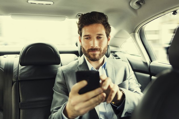 Hipster man in car Typing text message on mobile phone