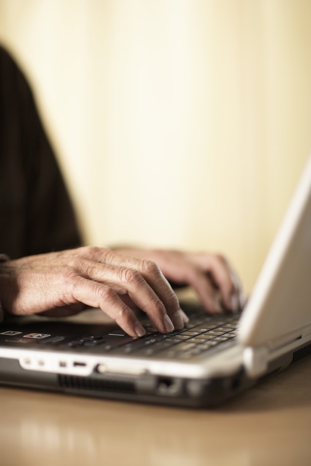 Senior man using laptop, close-up of hands