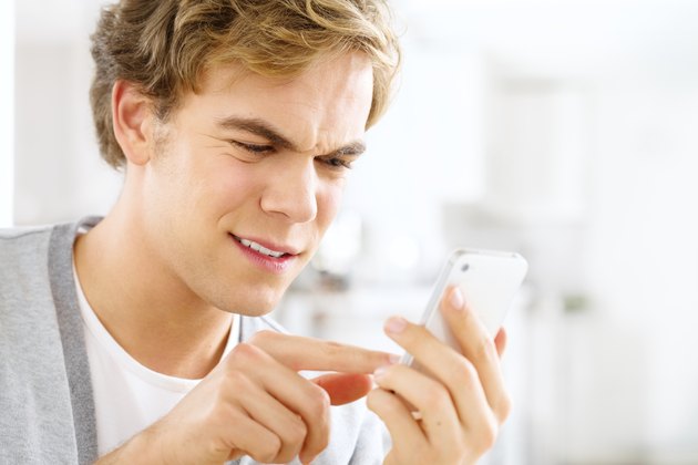 Frustrated man sending text message using mobile phone