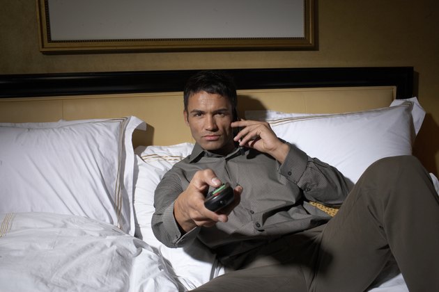 Man lying on bed, watching television