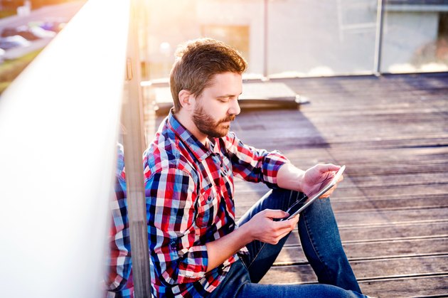 Businessman working from home on tablet, sitting on balcony