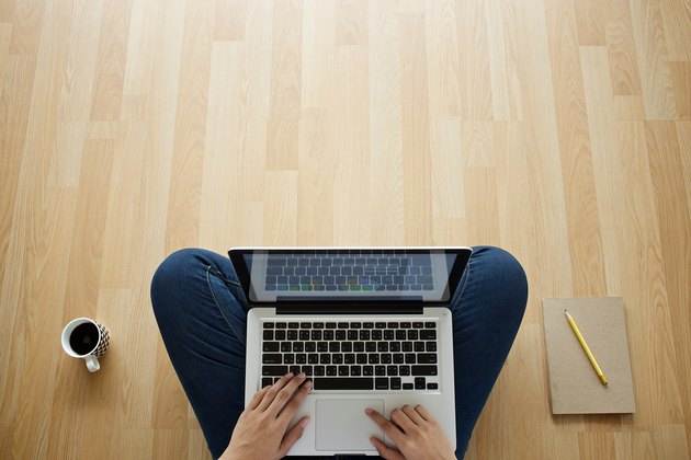 girl sitting on wooden floor laptop coffee cup and notebook