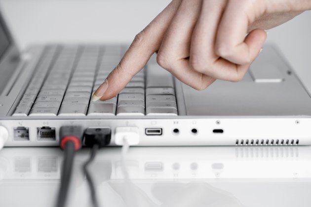 Hand with laptop computer with USB cords