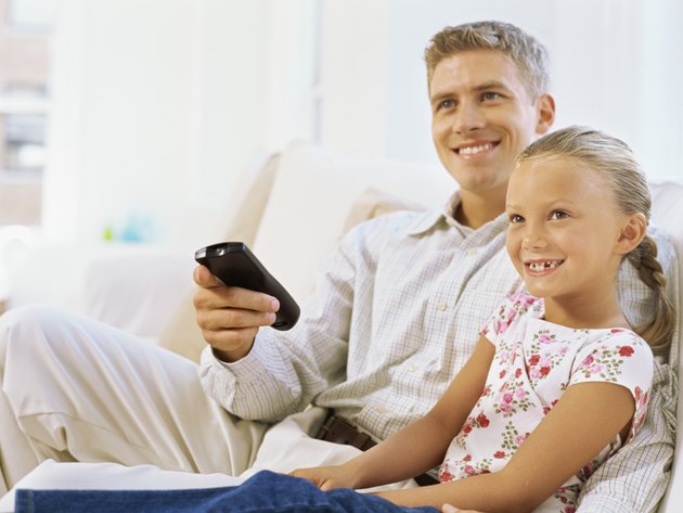 father sitting with his daughter holding a remote control