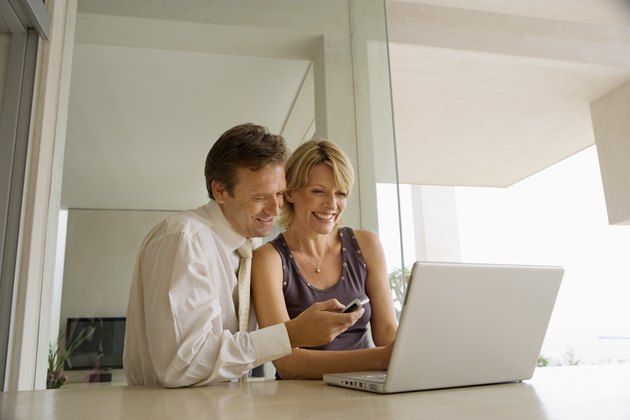 Couple using laptop and cell phone