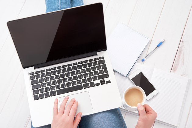woman working at home at laptop with cup of coffee